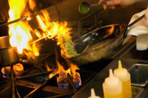 Chef cooking over a flaming stove.