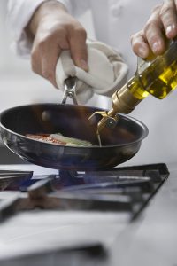Chef cooking food in frying pan close-up